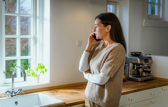 kvinde taler i telefon i sit køkken